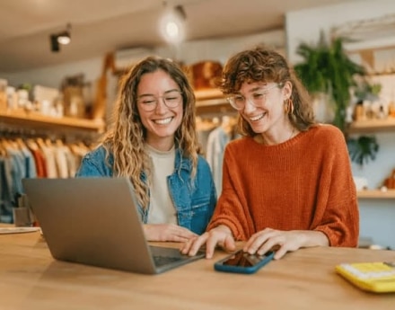 Empresárias em sua loja de roupas, mexendo no notebook