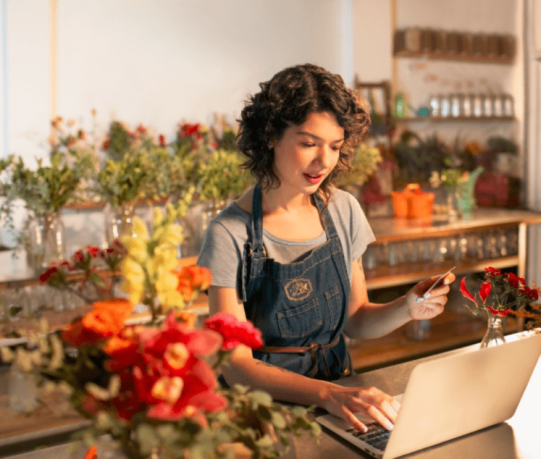 Imagem de uma florista mexendo em um notebook em uma floricultura