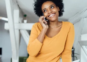 Mulher sorrindo enquanto fala ao celular.