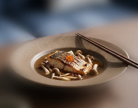 Filé de peixe com cogumelos e molho, acompanhado de hashis.
