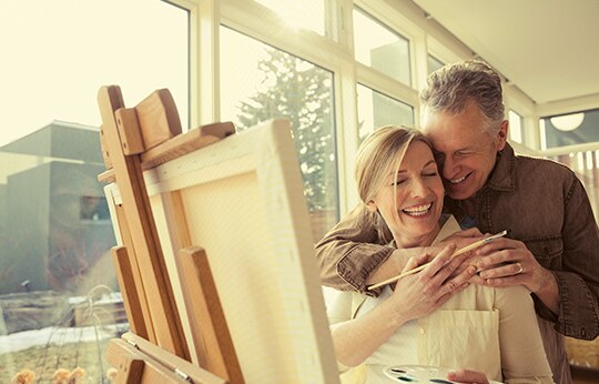 casal de idosos itau personnalite se abraçando em frente a um quadro