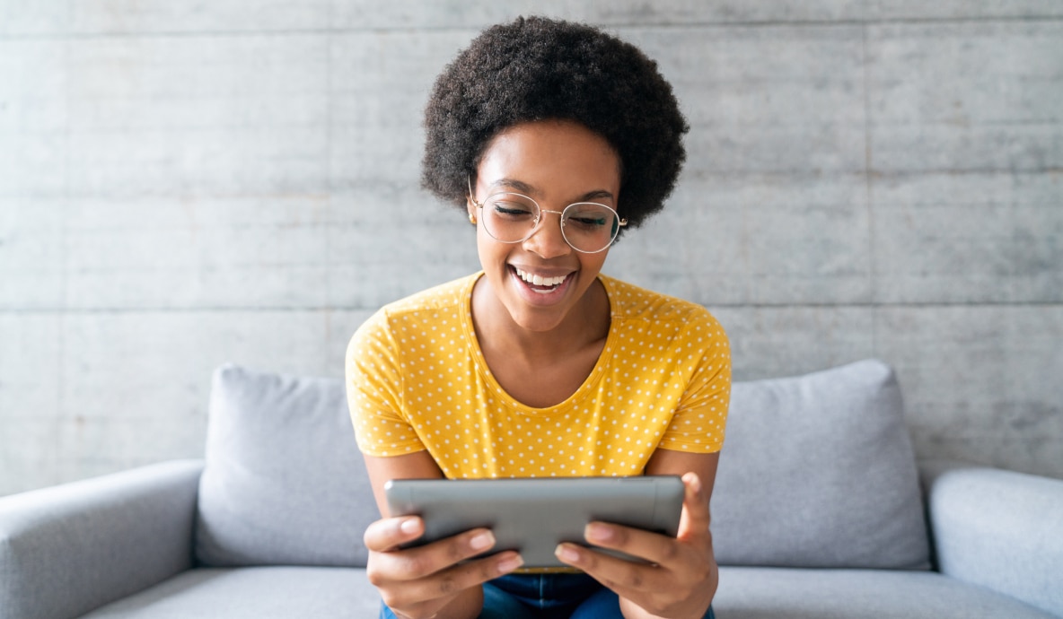 Mulher, sentada no sofá, usando seu tablet