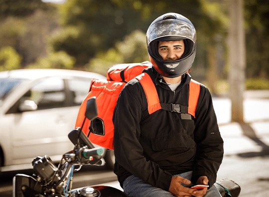 pessoa de capacete encostado numa moto