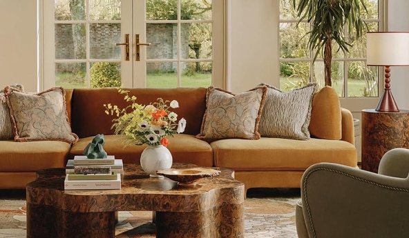 Sala com sofá, almofadas, mesa de centro e arranjo de flores.
