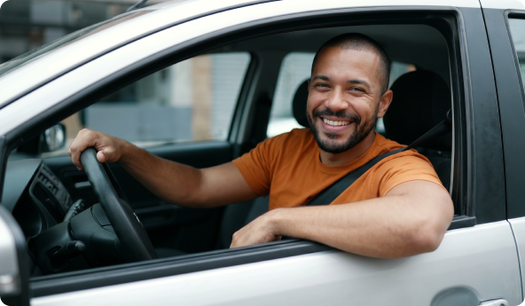 Homem ao volante de veículo com braço apoiado na janela.
