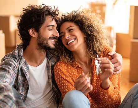 Duas pessoas sentadas no chão em ambiente com caixas de mudança.