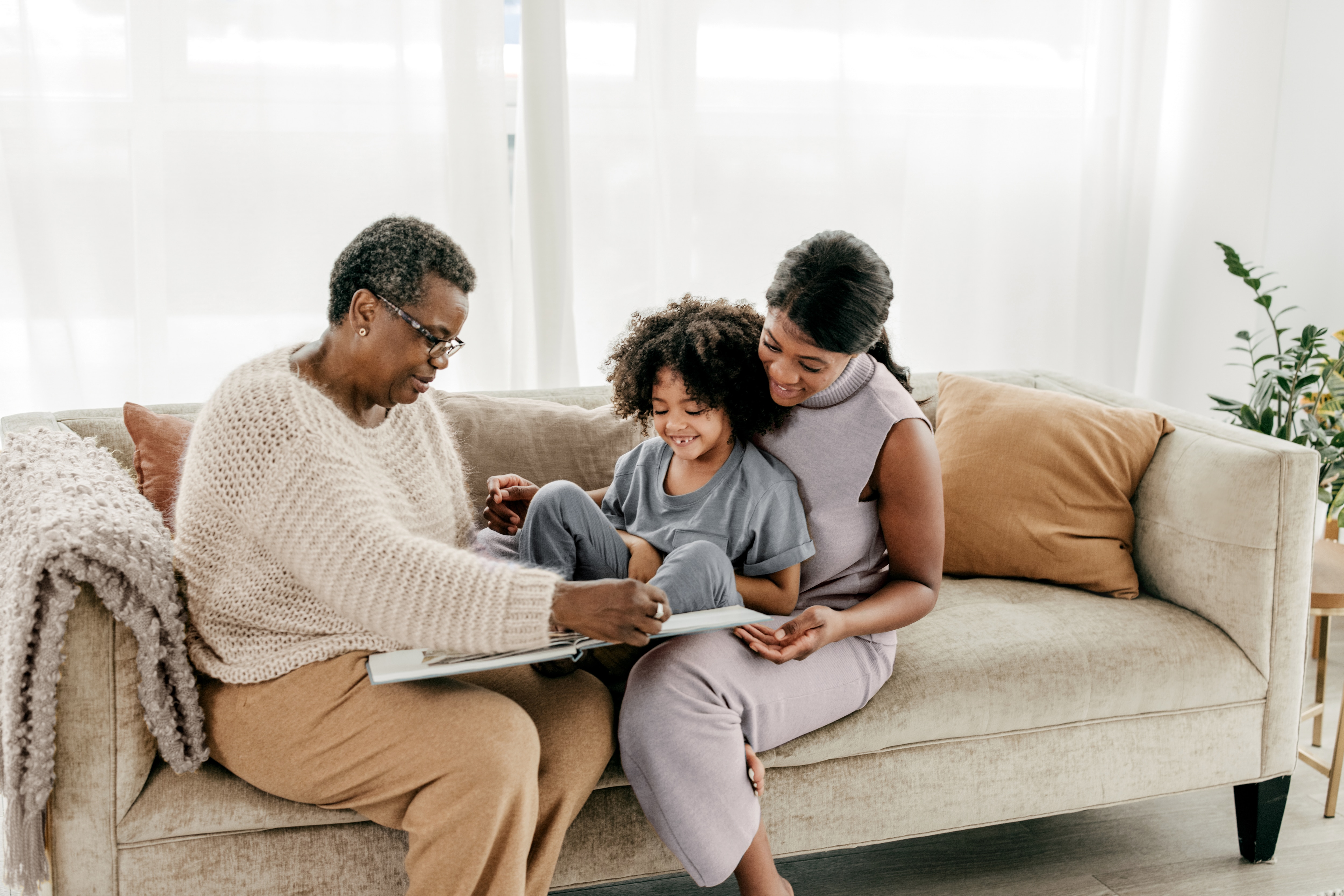 Família no sofá, mãe, avó e criança sorrindo, clientes Itaú Private Bank Testamento.