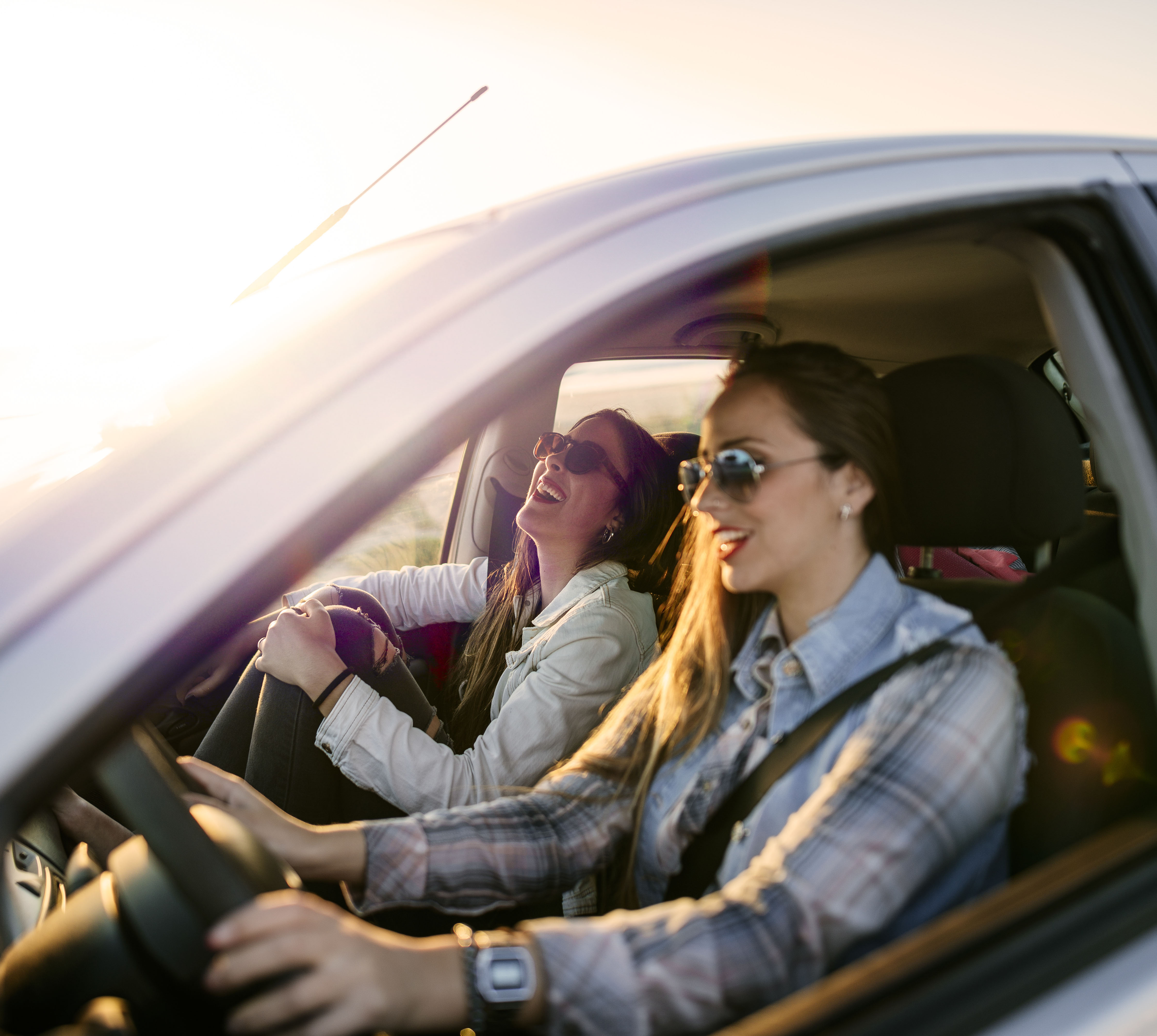 Mulheres sorrindo no carro com tranquilidade de ter Porto Seguro Auto